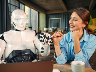 robot and woman working on laptop in office