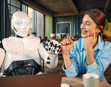 robot and woman working on laptop in office